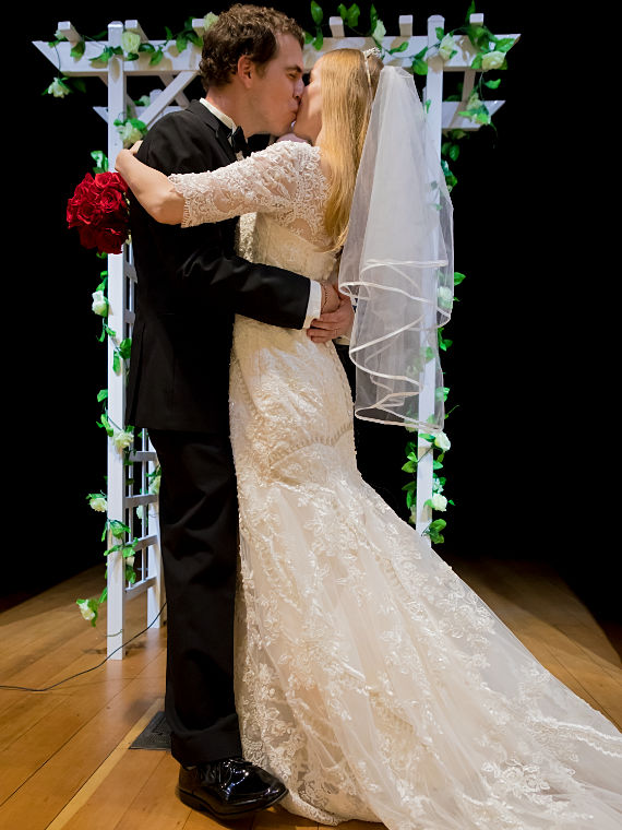 Brautpaar Kuss vor Rosenbogen