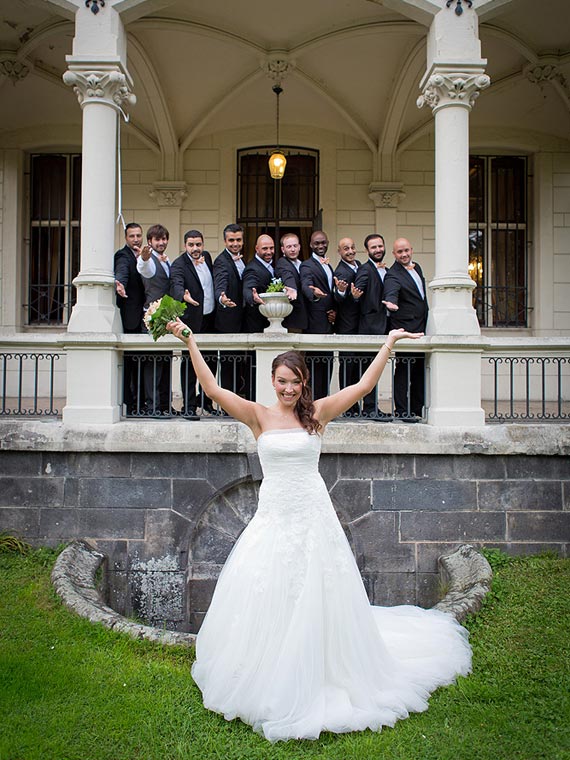 Braut streckt Arme in die Luft, mit Bräutigam und Freunden