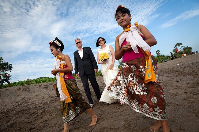 Vater und Braut bei Strandhochzeit Bali, begleitet von Tänzerinnen