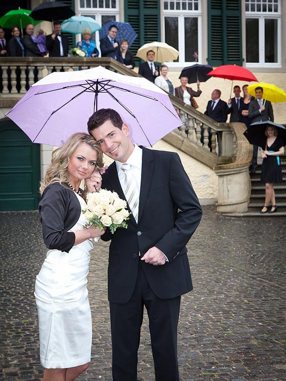 Hochzeitsgesellschaft mit Regenschirmen