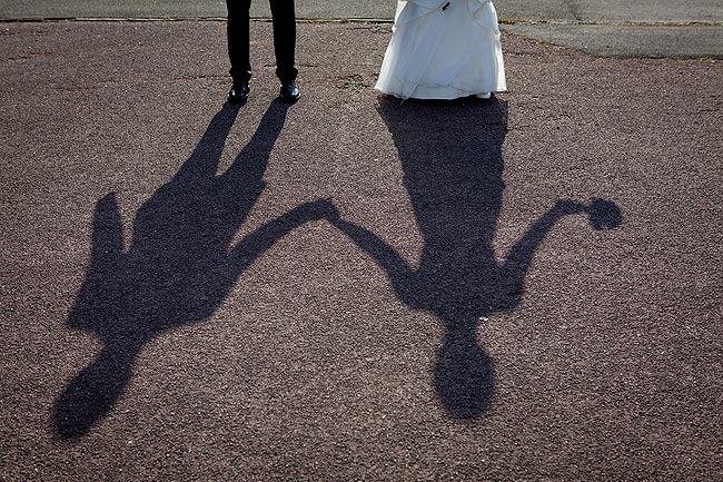 Brautpaar wirft Schatten auf Asphalt mit Hochzeitsbouquet